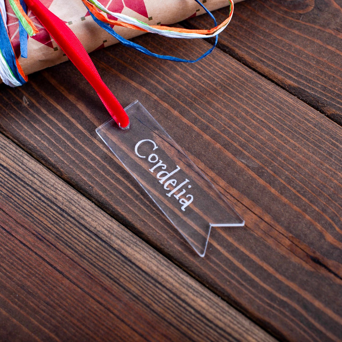 Close-up of laser-engraved clear acrylic gift tag reflecting fairy lights