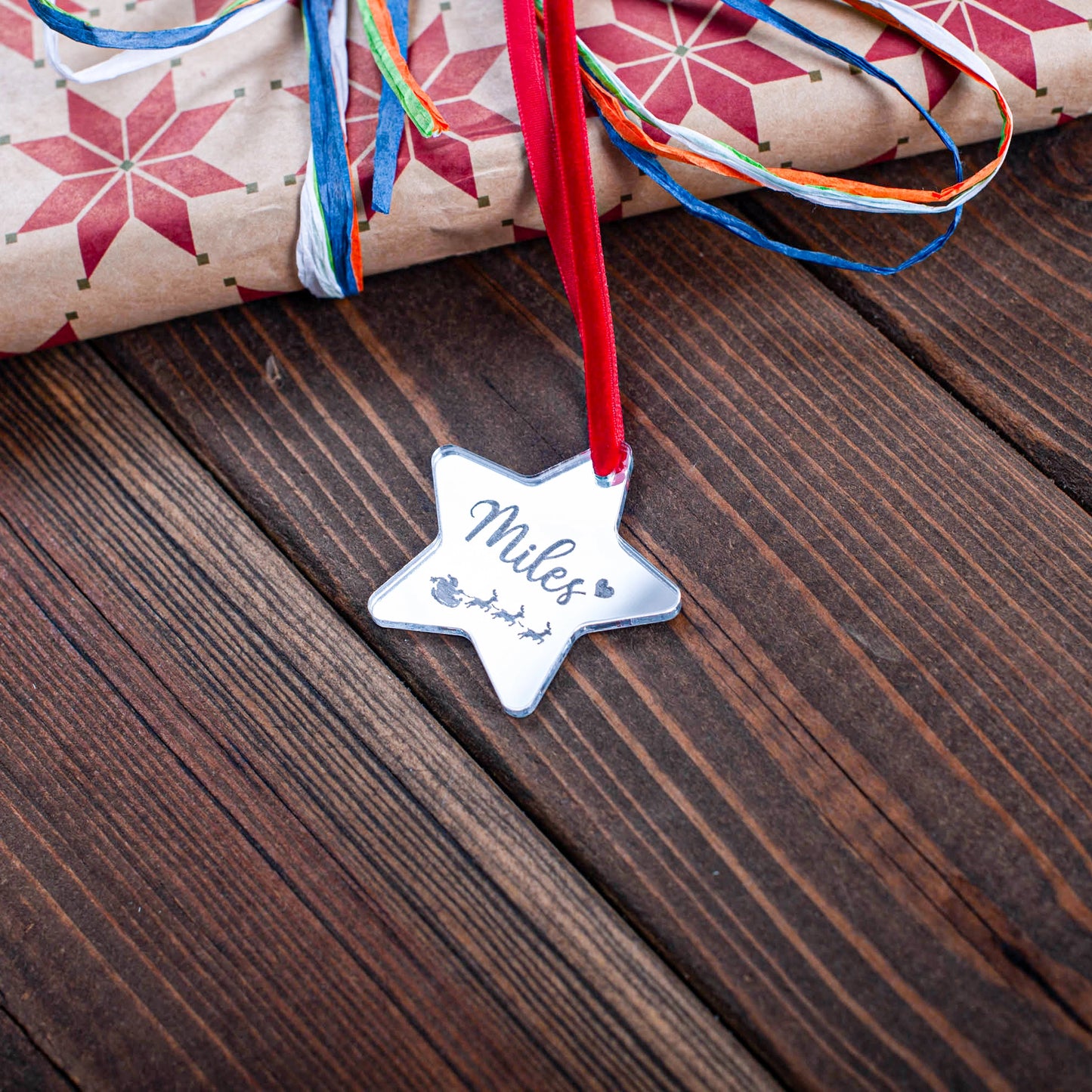Engraved silver mirror star tag on wrapped Christmas present
