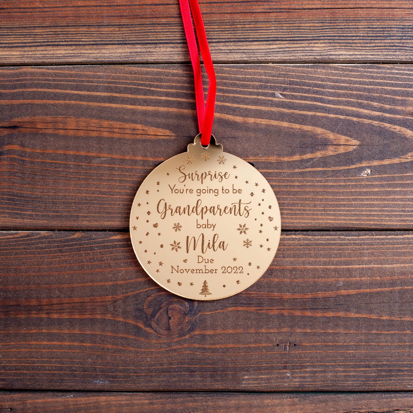 Engraved ornament announcing baby on the way hanging on tree