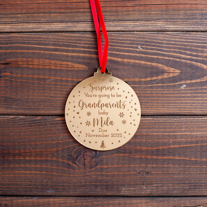Engraved ornament announcing baby on the way hanging on tree