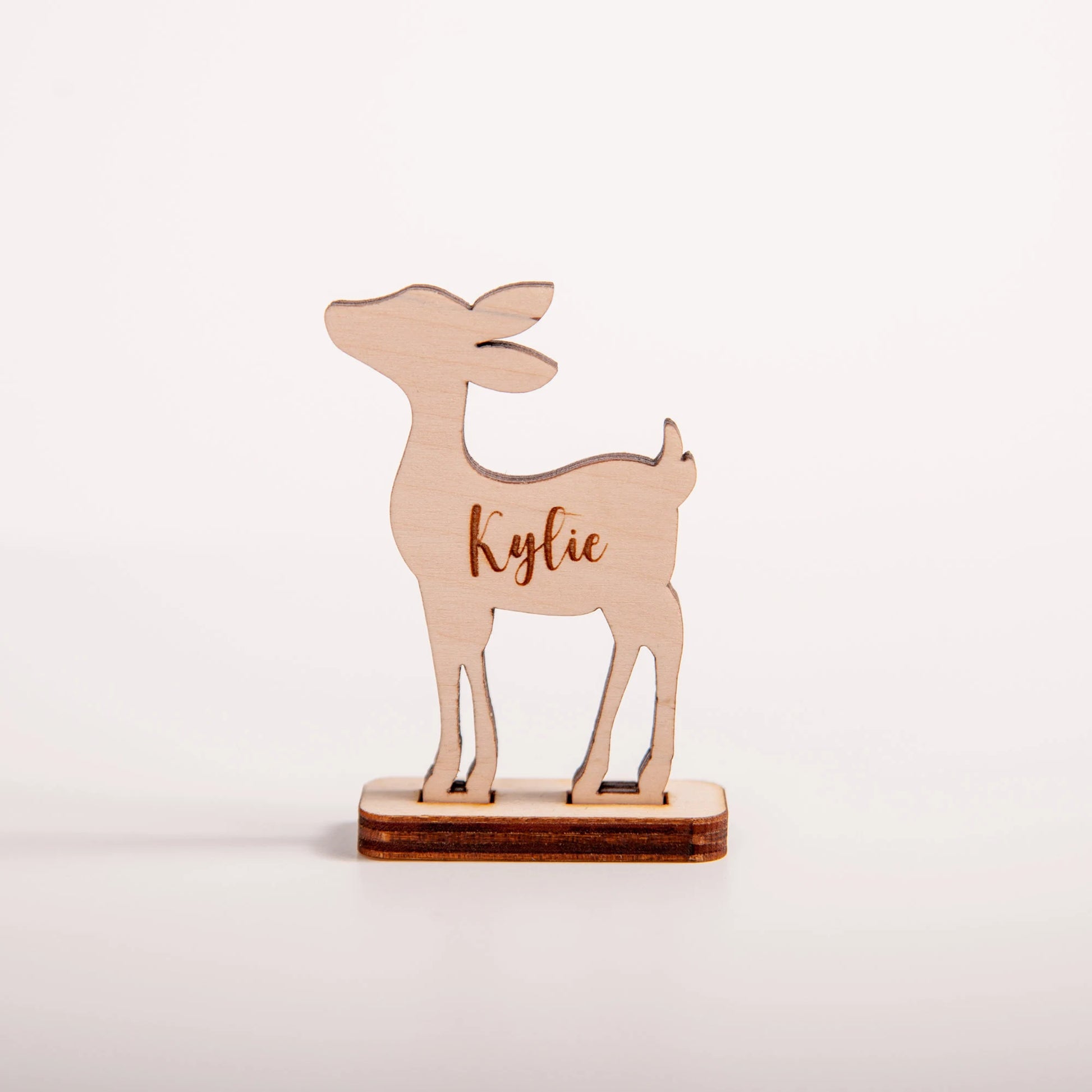 Wooden reindeer figurine with name engraving on a light pink background