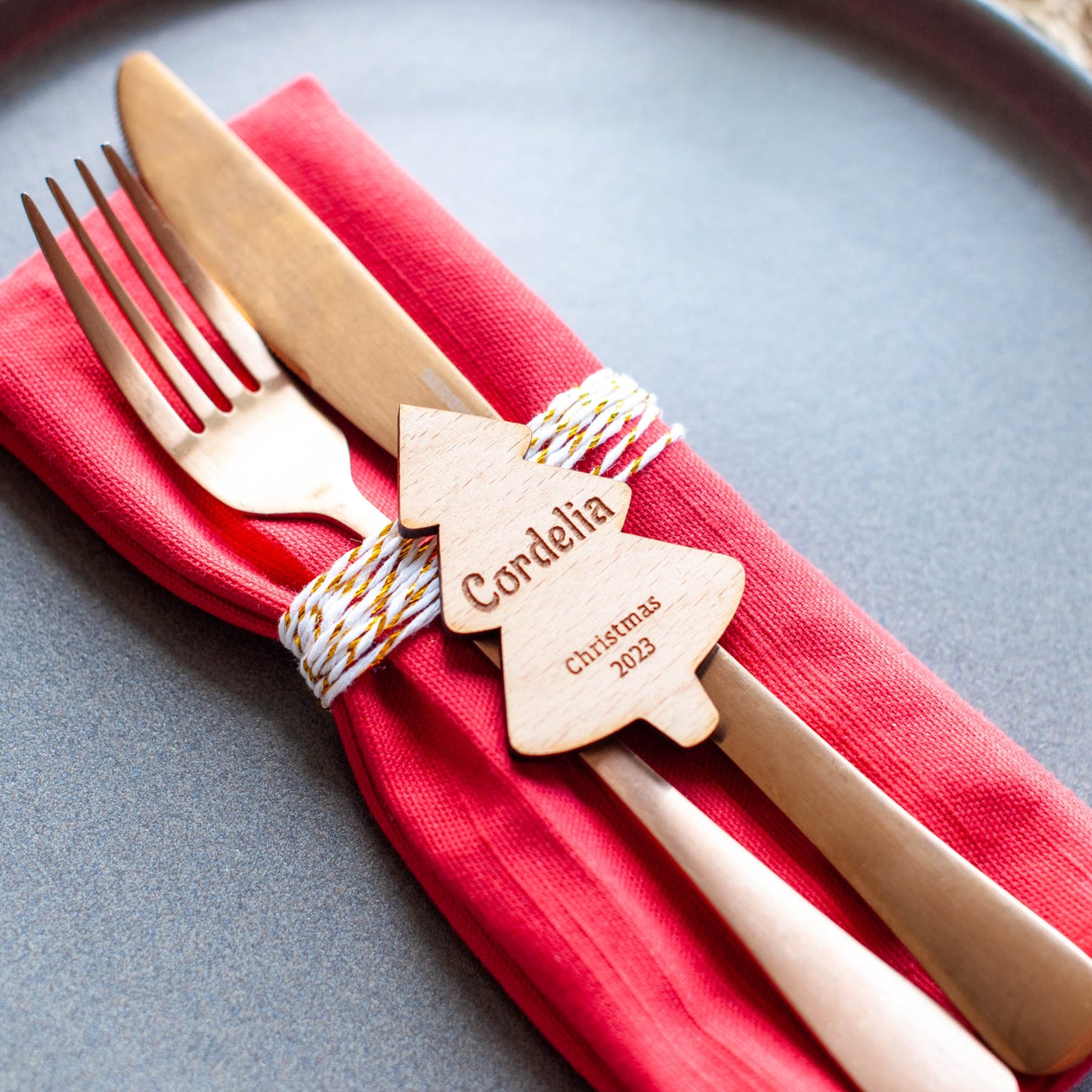 Close-up of engraved Christmas tree name tag on red napkin