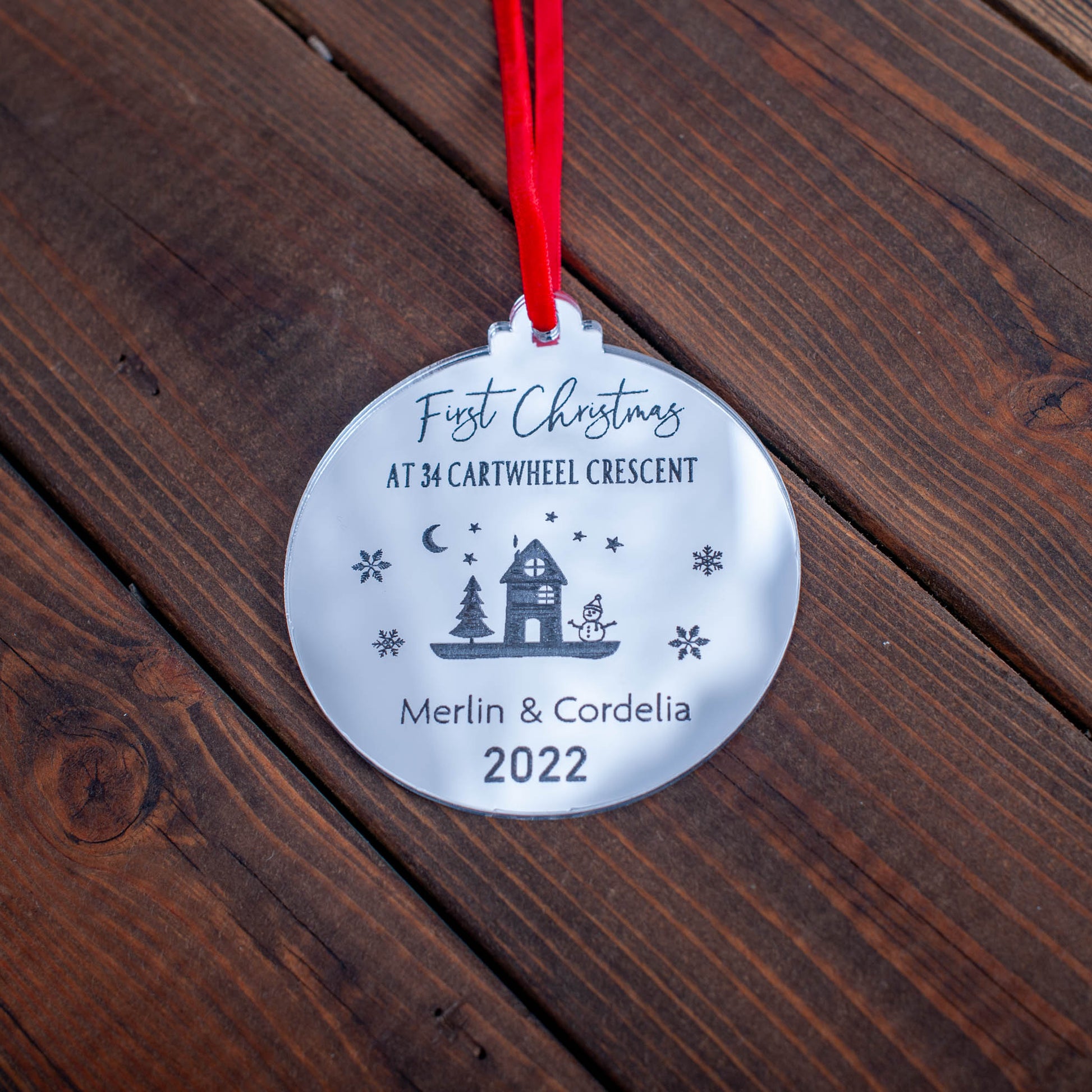 Engraved wooden first home ornament hanging on Christmas tree branch
