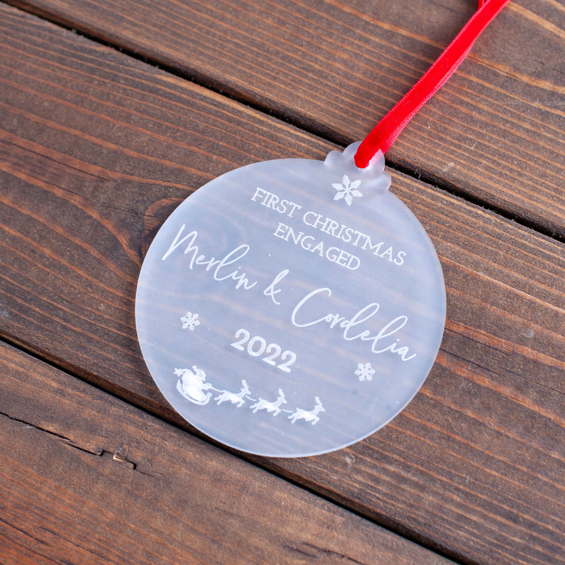 Elegant first Christmas engaged ornament hanging on festive tree