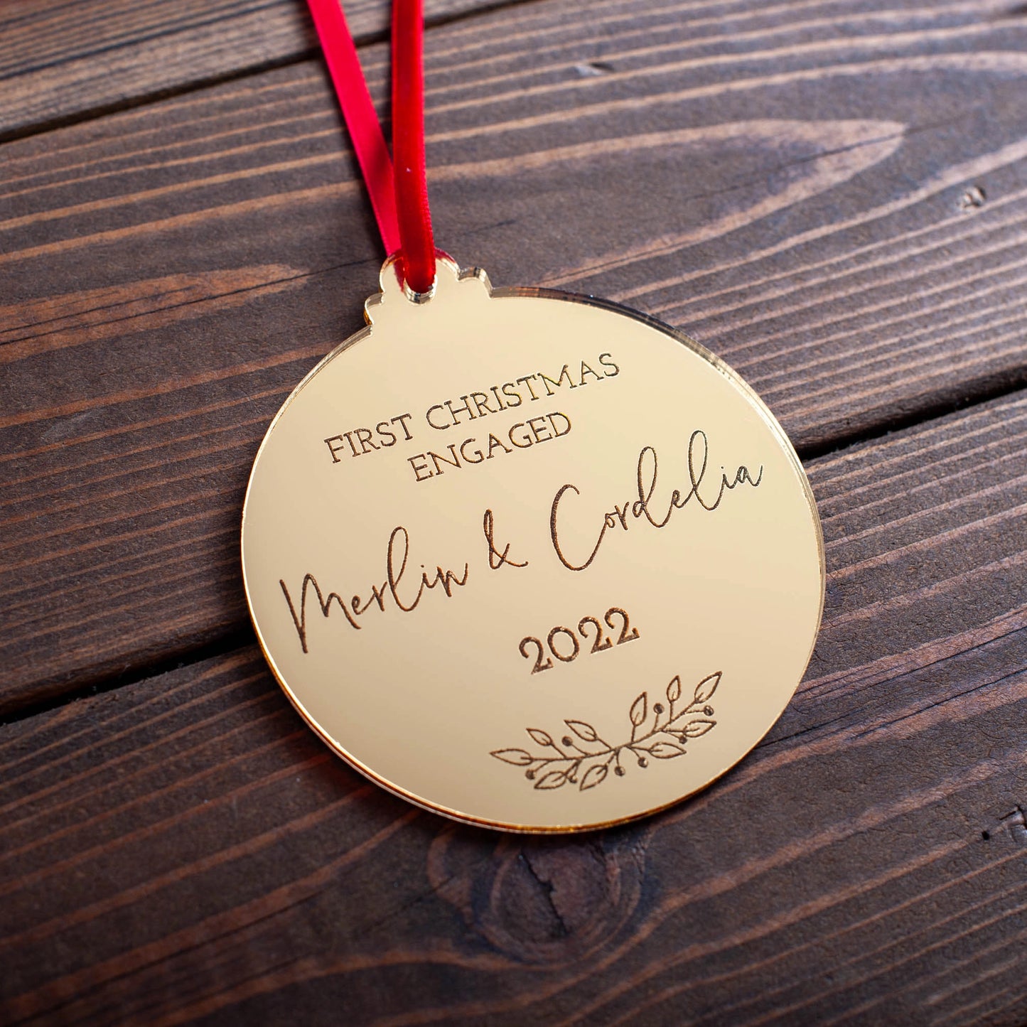 Gold mirror Christmas ornament engraved with engaged couple’s names and year