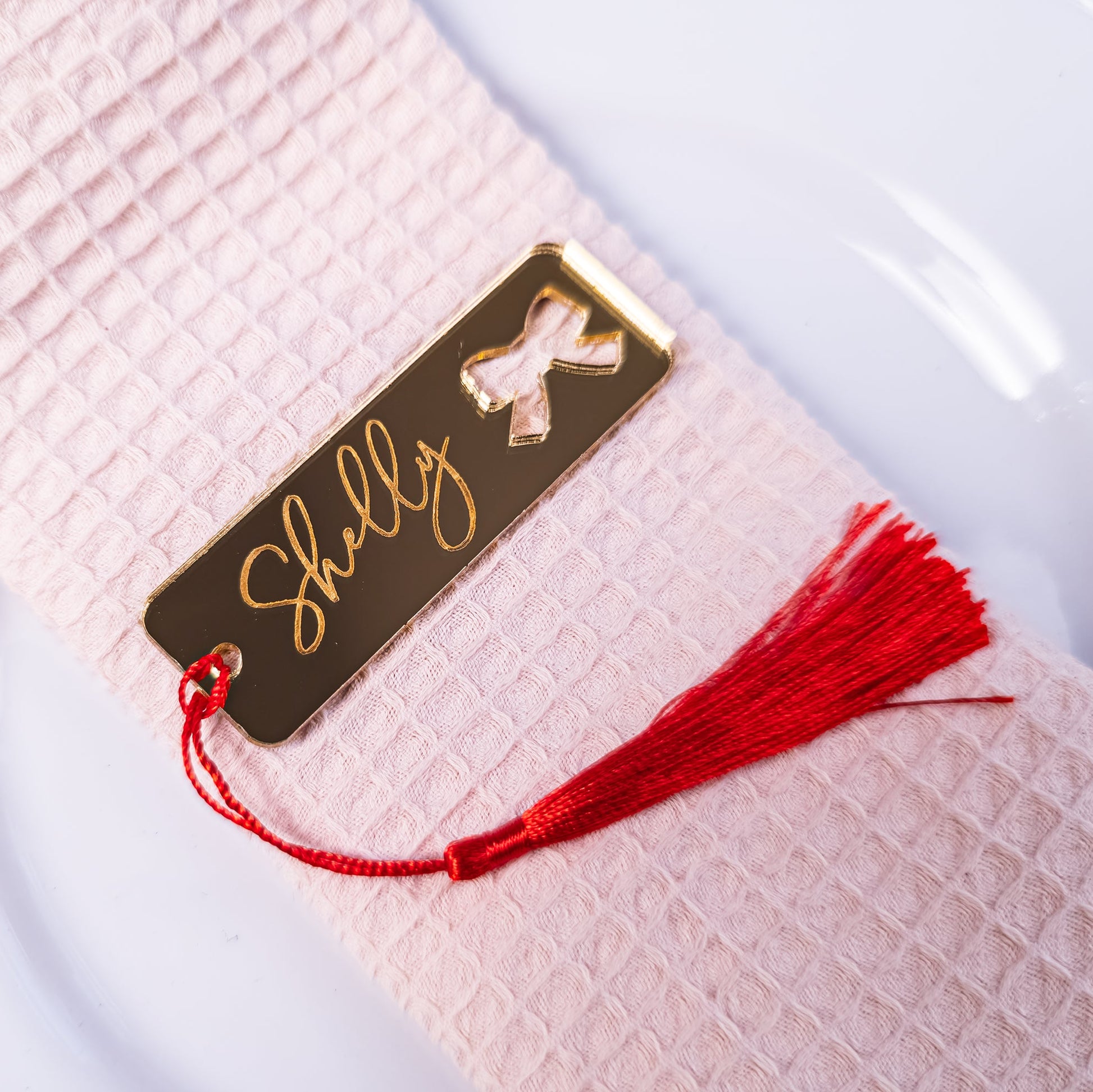 Gold name tag with red tassel on a textured white surface
