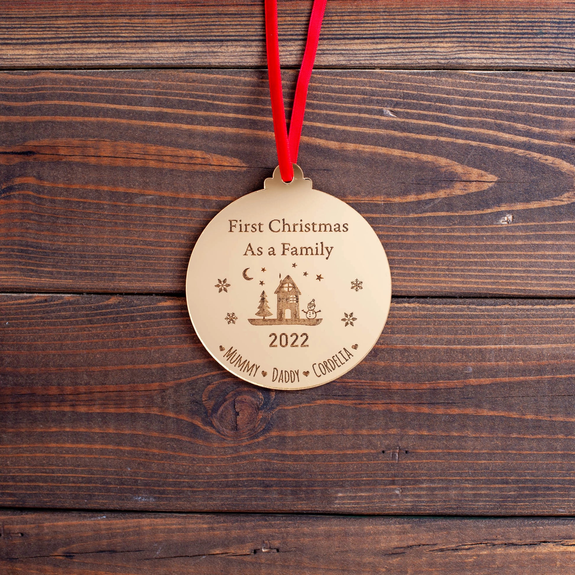 Elegant gold acrylic family bauble hanging on tree branch