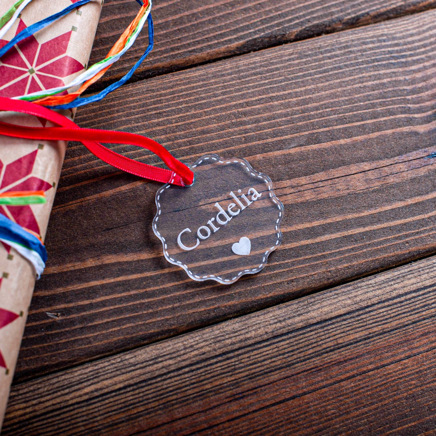 Engraved acrylic Christmas gift tag with ribbon attached to wrapped present