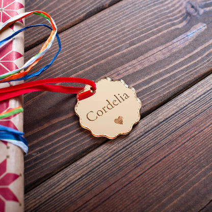 Close-up of engraved gold mirror acrylic bauble reflecting fairy lights