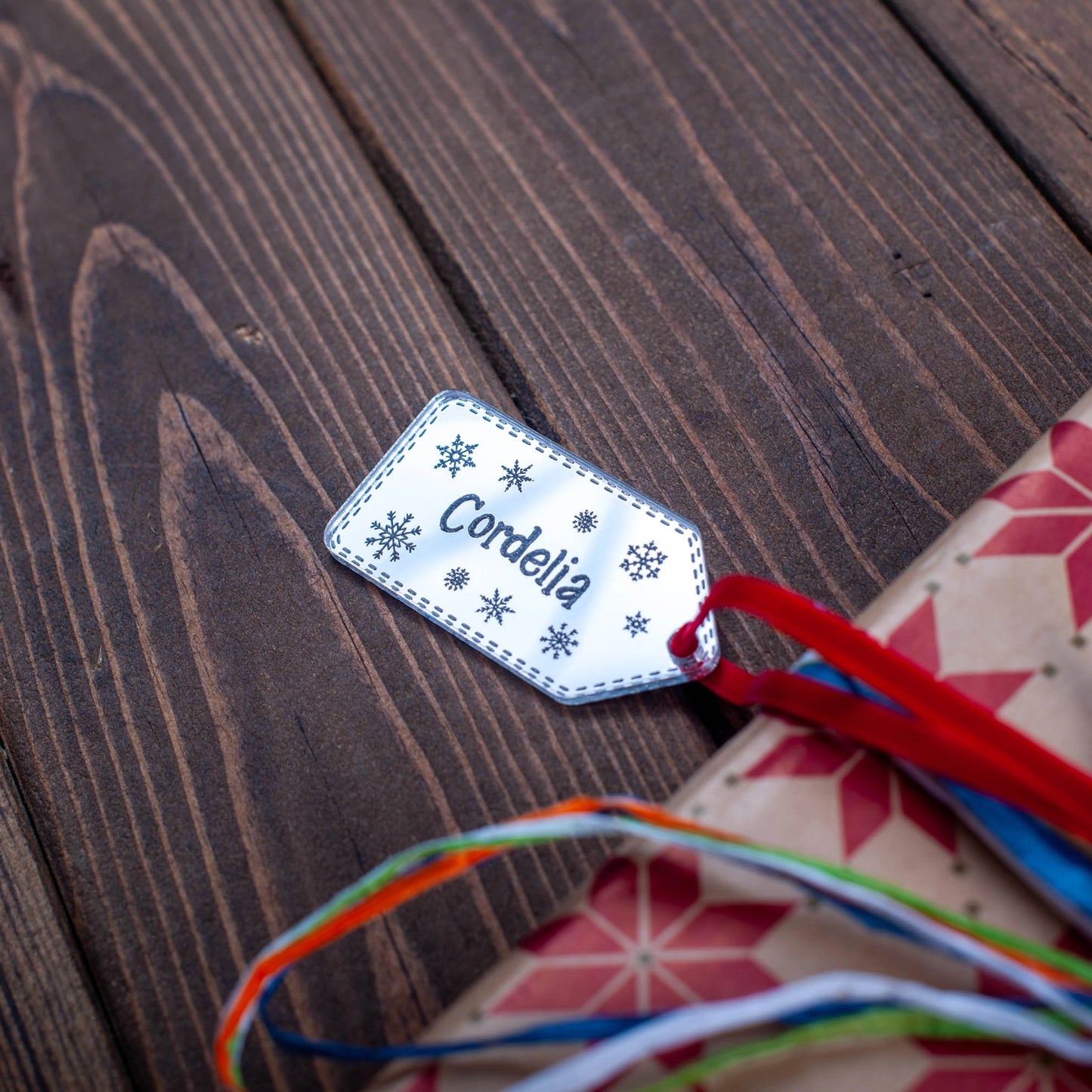 Engraved silver mirror snowflake tag on wrapped Christmas present