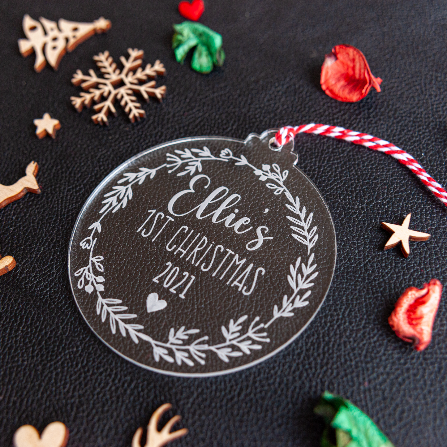 Personalised clear acrylic bauble engraved with baby’s name and 2025, hanging on a Christmas tree with warm fairy lights.