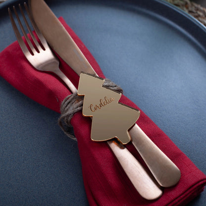 Gold mirror Christmas name tag on white napkin and festive tableware