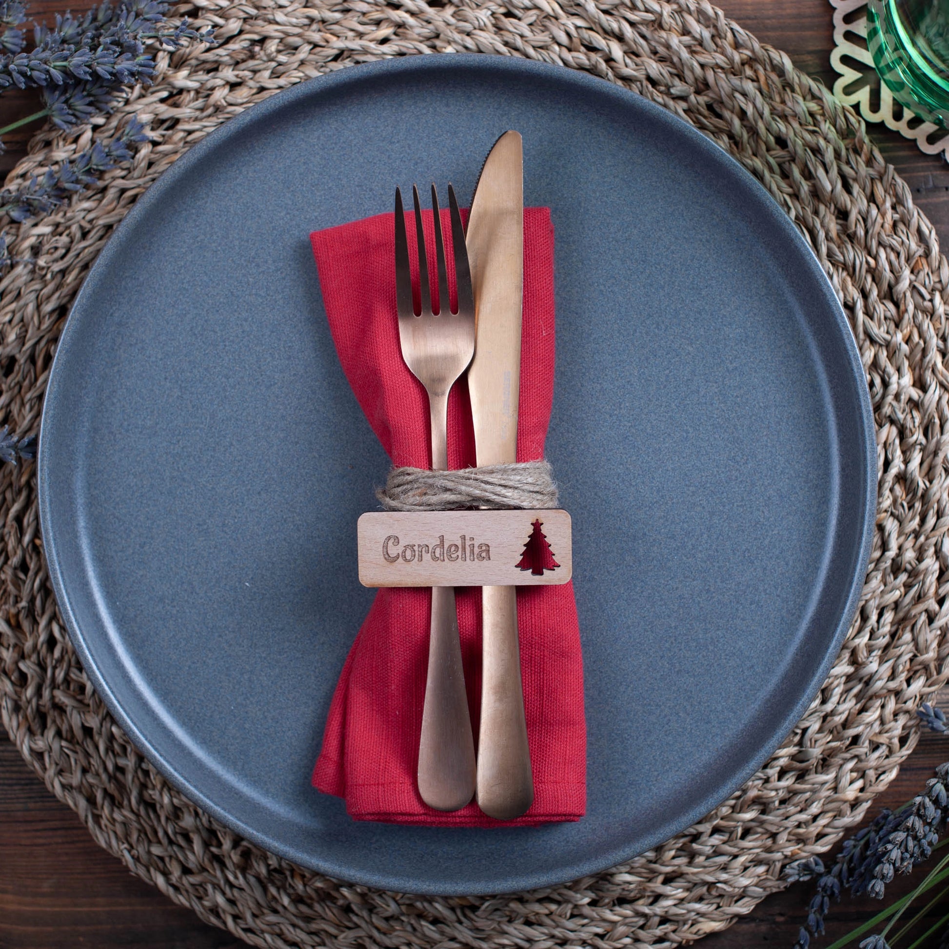 Overhead shot of engraved wooden rectangle name tags with ornament cutouts on a rustic table