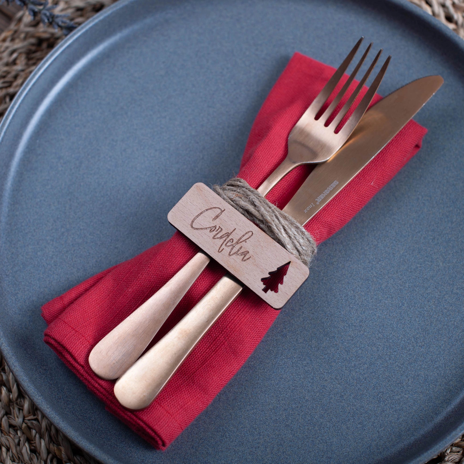 Overhead view of rustic wooden place settings engraved with names and festive ornaments