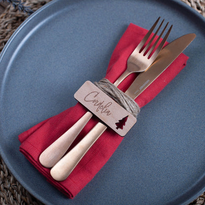 Overhead view of rustic wooden place settings engraved with names and festive ornaments