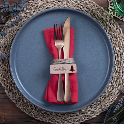Wooden name tags with ornament cutouts arranged flat on Christmas table runner