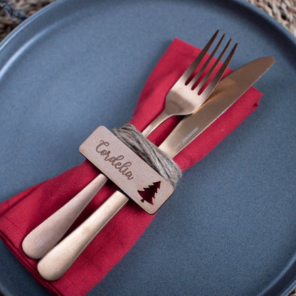 Rustic Christmas flat-lay showing personalised wooden table name cards on linen cloth