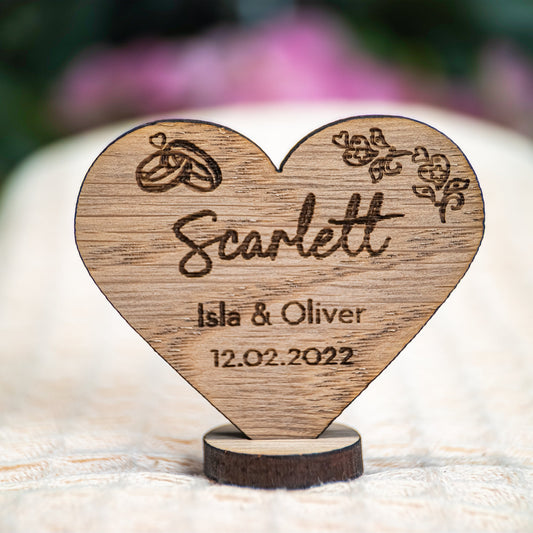 Wooden heart-shaped ornament with engraved name 'Scarlett' and dates on a blurred background