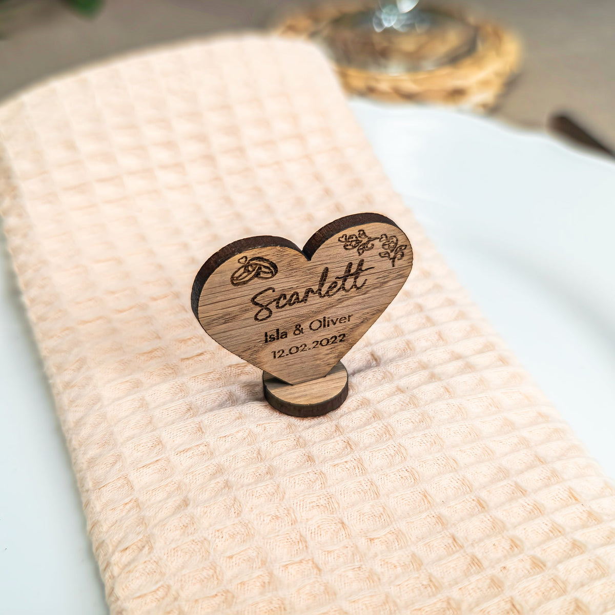 Wooden heart-shaped place card holder on a white plate with a beige napkin