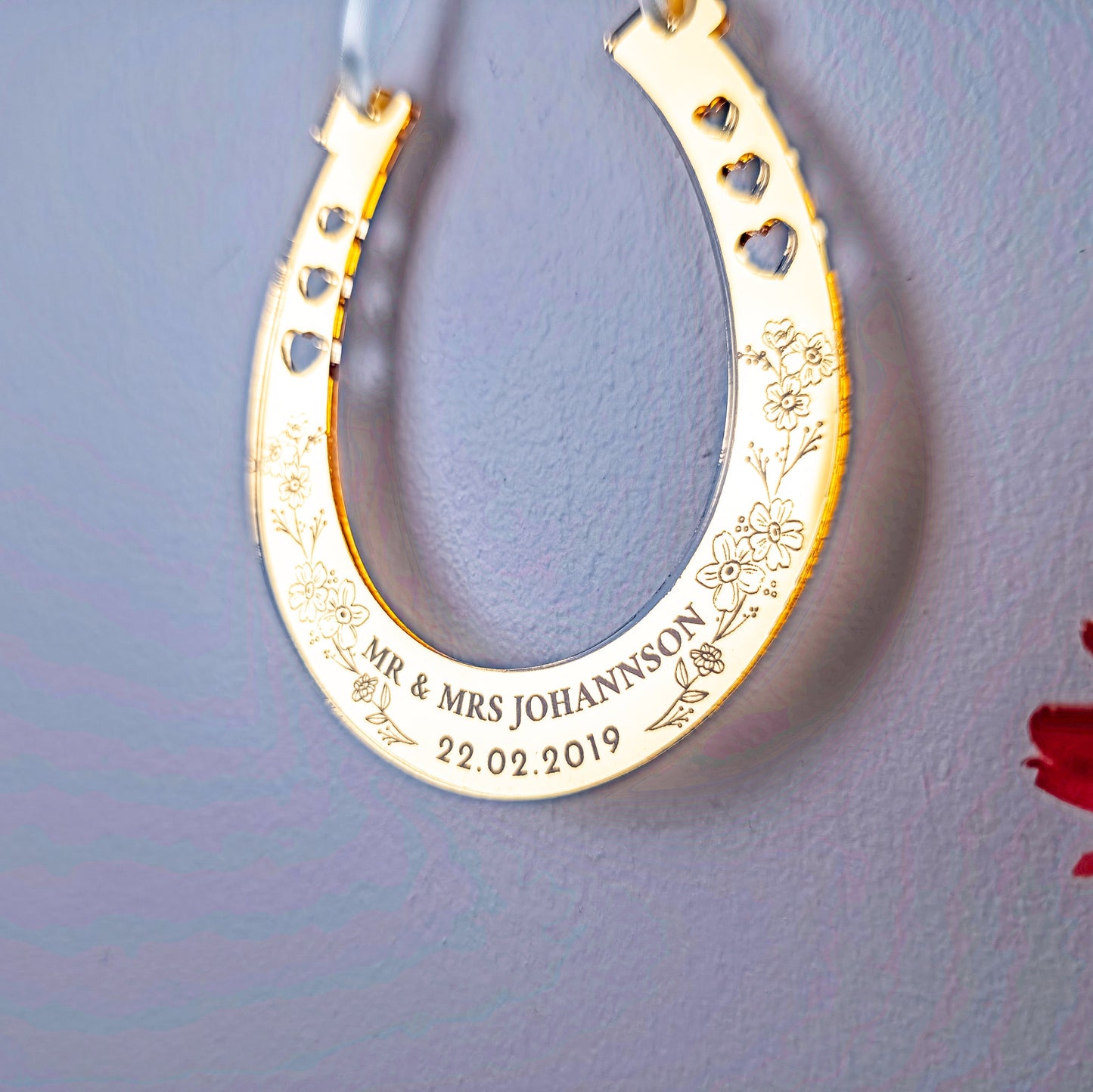 Gold horseshoe ornament with engraved text on a gray background