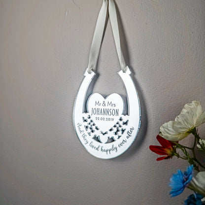 Decorative horseshoe with engraved text on a gray wall with flowers.