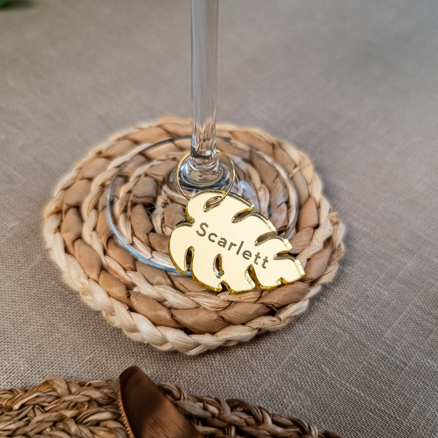 Monstera leaf wine charm attached to champagne glass with engraved name