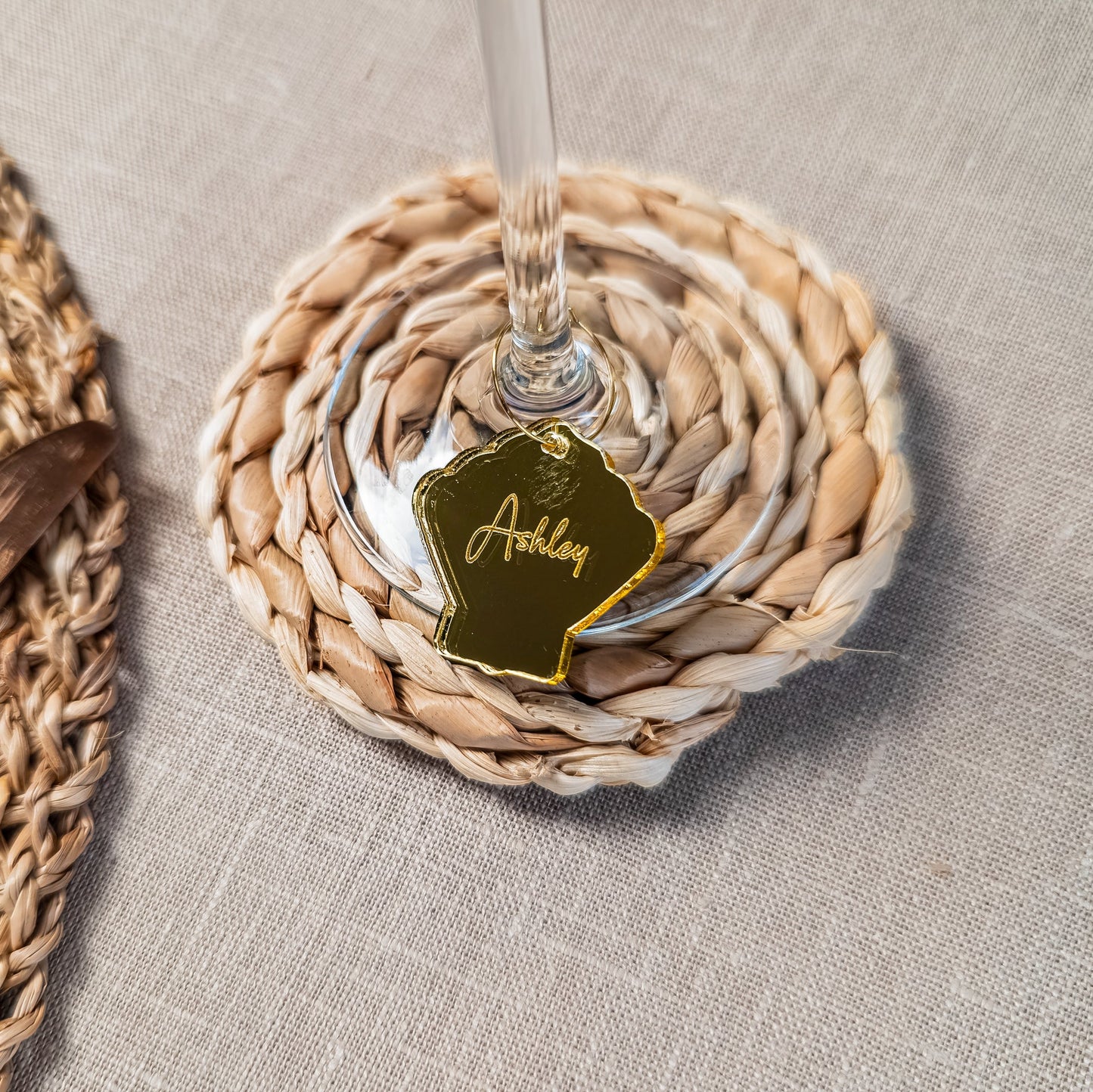 Woven coaster with a glass of wine and a name tag on a textured surface