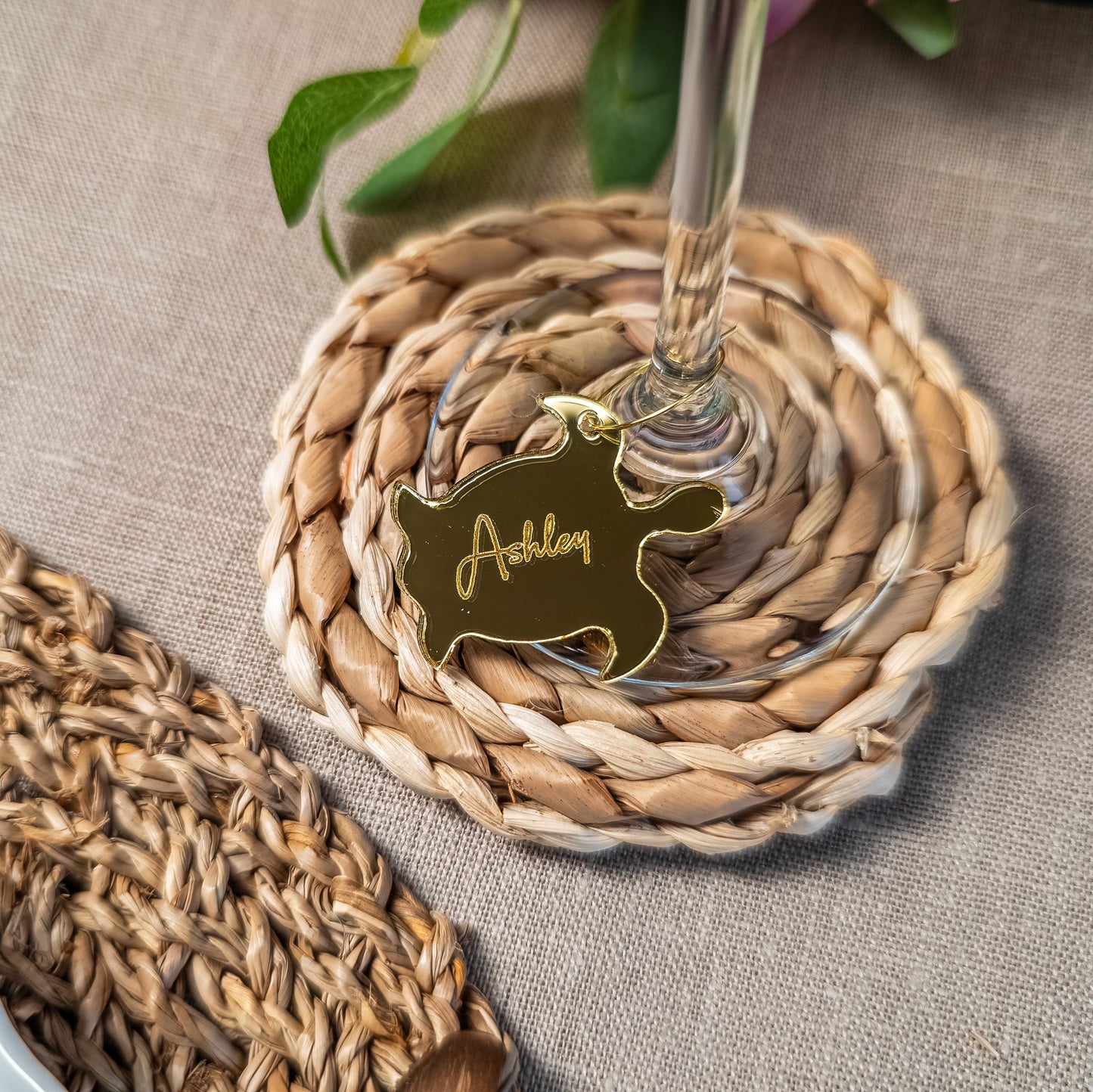 Woven coaster with a glass holder and personalized tag on a textured surface