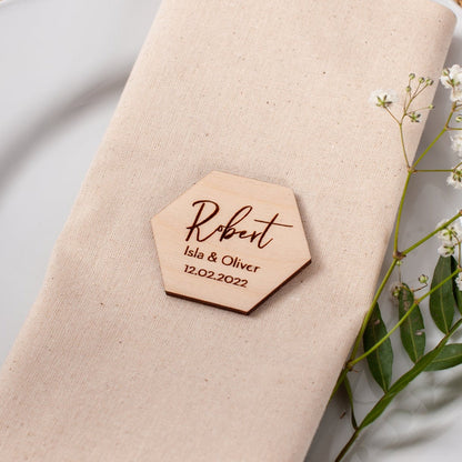 Napkin with a wooden name tag on a white plate with a woven placemat.