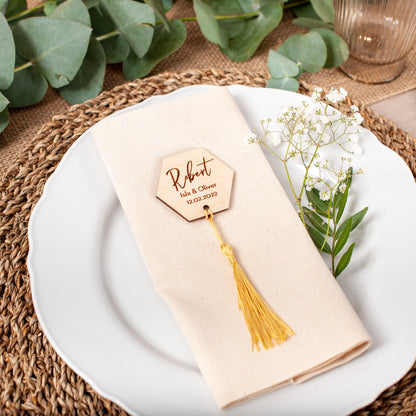 Table setting with a place card holder, napkin, and flowers on a white plate.