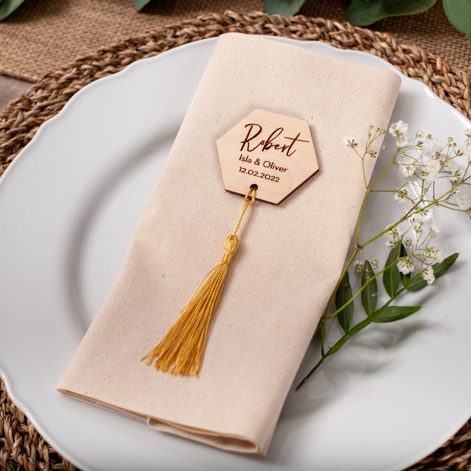 Napkin with a decorative name tag on a white plate with a woven placemat.